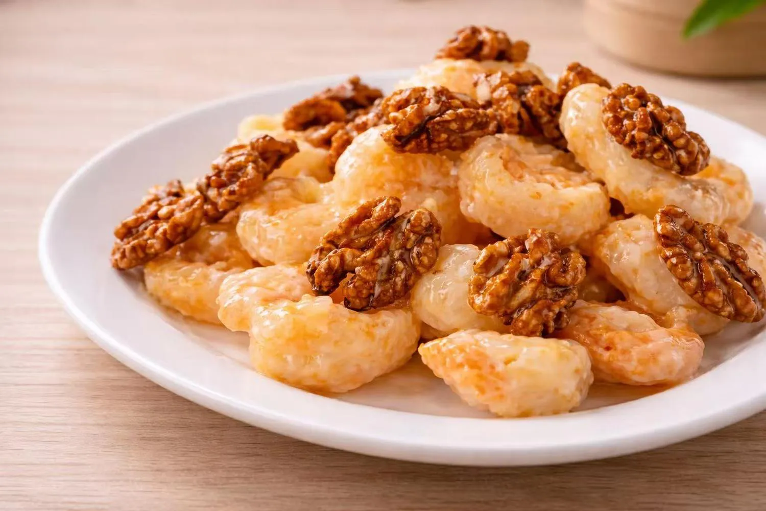 Creamy walnut shrimp topped with candied walnuts on a white plate