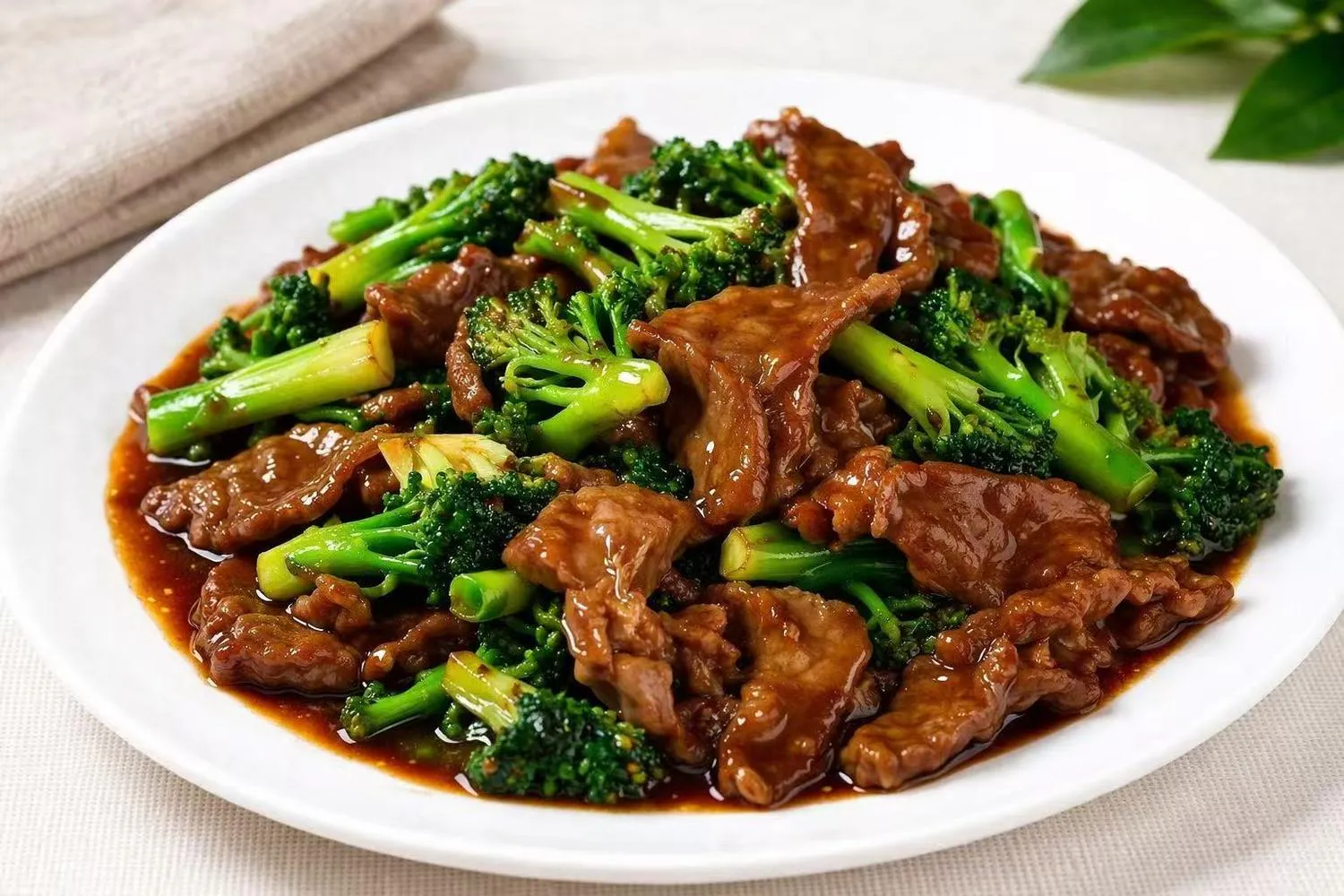 Beef and broccoli stir-fry in a glossy brown sauce on a white plate